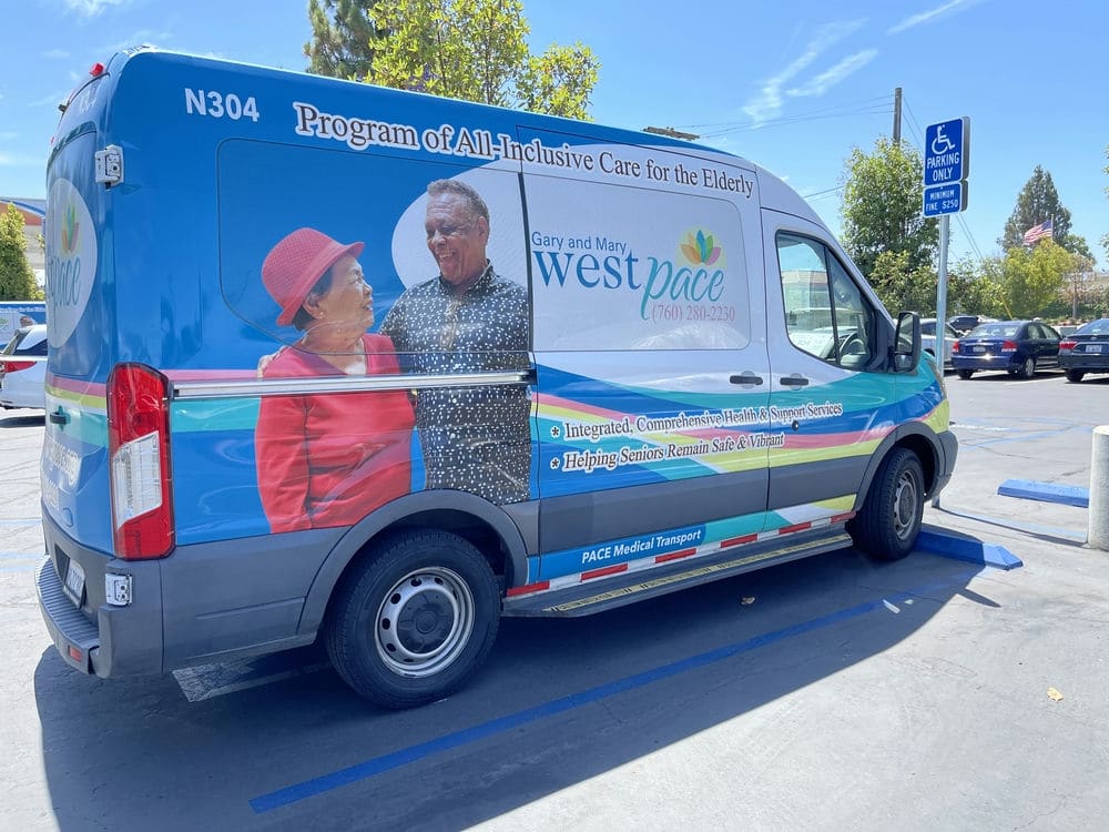 West PACE team member helping a man in a wheelchair into a support vehicle